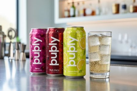 Chilled bubly POP cans and a clear highball glass with sparkling bubbles on a modern bar counter.